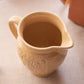 Medium Tan Ceramic Pitcher with Floral Details